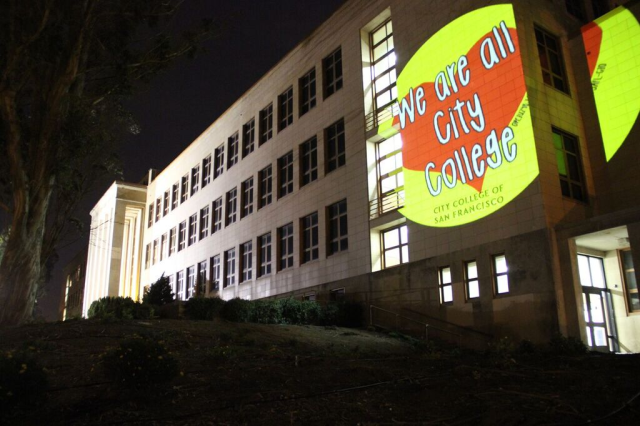 A projector puts an image on the side of the main City College building